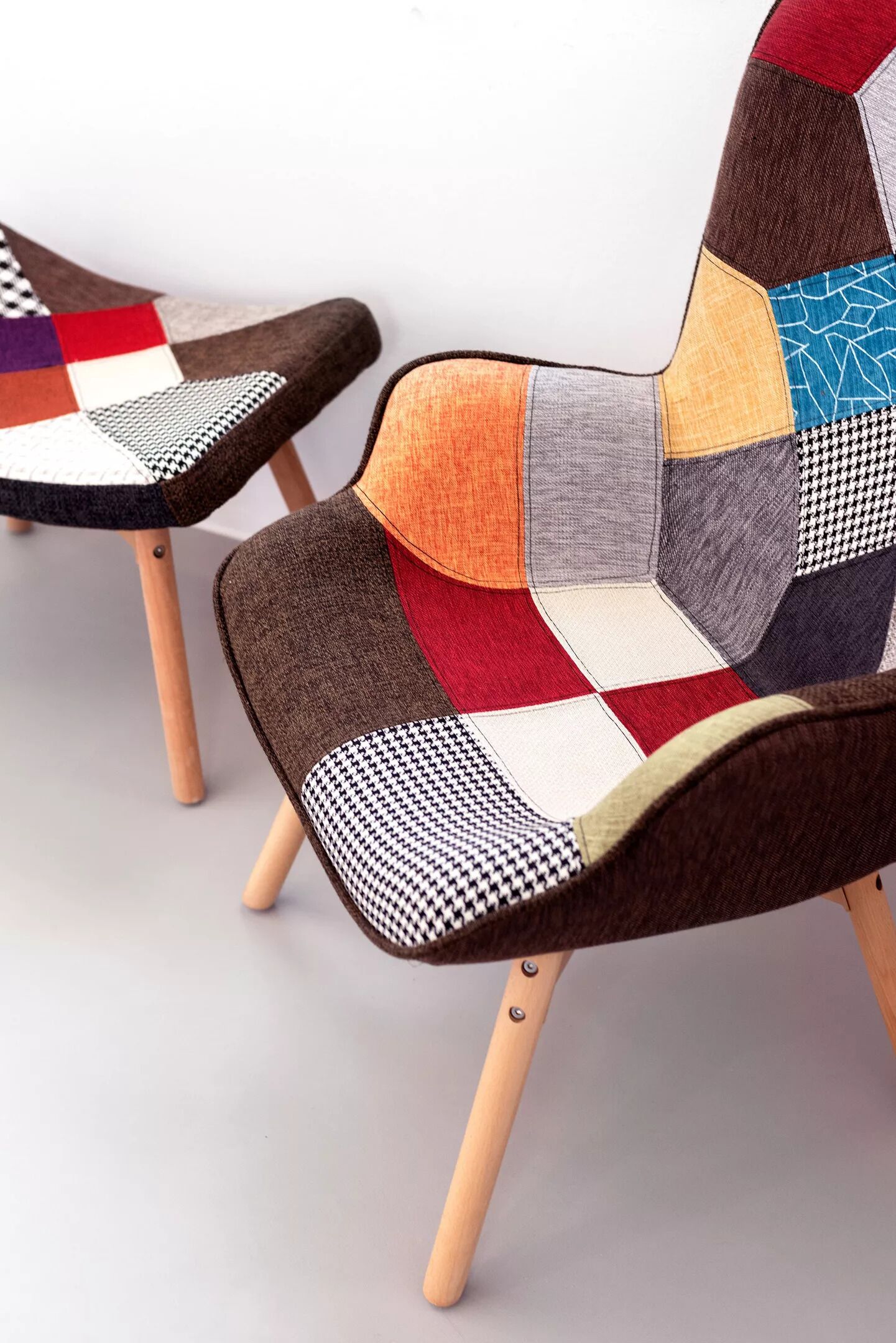 Two chairs with a patchwork design and wooden legs.