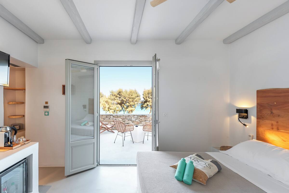 Ein modernes Hotelzimmer mit Bett, einer Kaffeemaschine, einem Fernseher und einem Balkon mit Sitzgelegenheit.