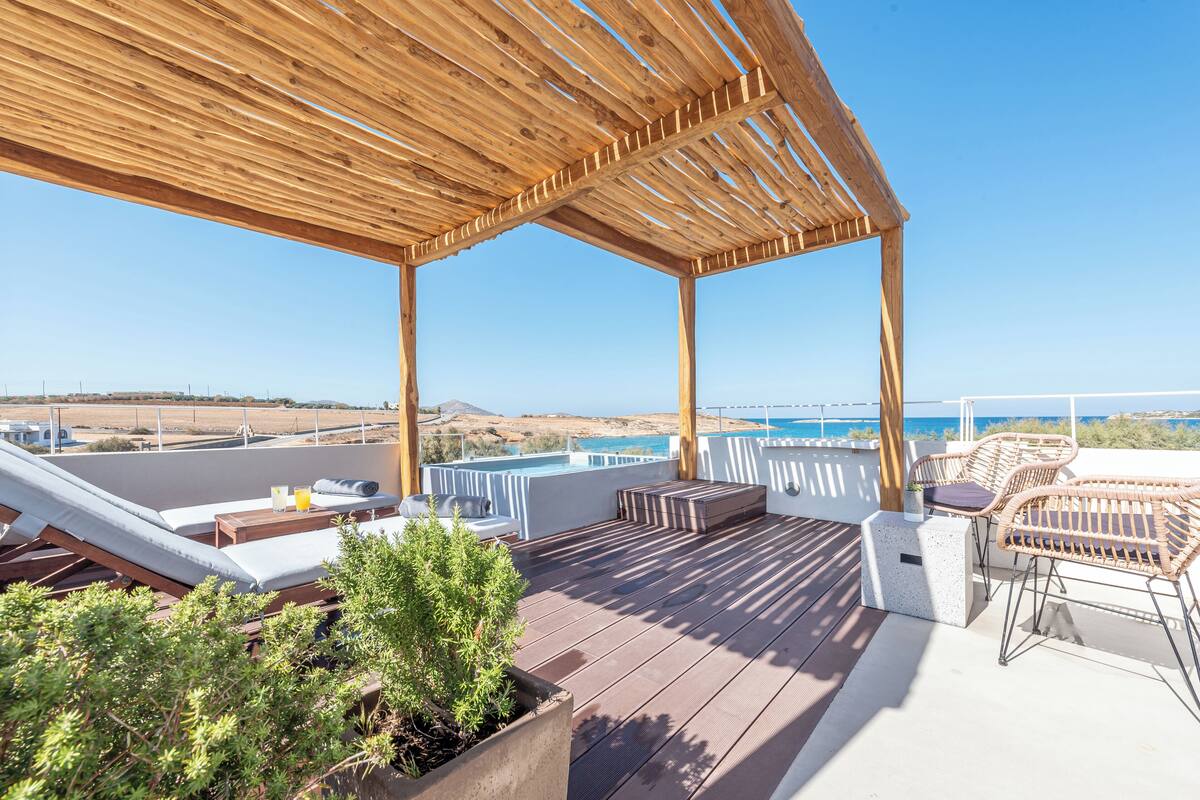 Eine Holzterrasse mit Liegestühlen, einem kleinen Tisch und einem Blumentopf.