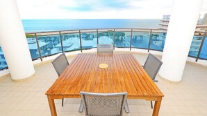 A wooden table with four chairs on a balcony with a view of the sea. - Residence Sky (Lignano Sabbiadoro)