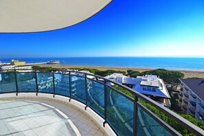 A high-rise building with a glass balustrade overlooking a beach. - Residence Sky (Lignano Sabbiadoro)
