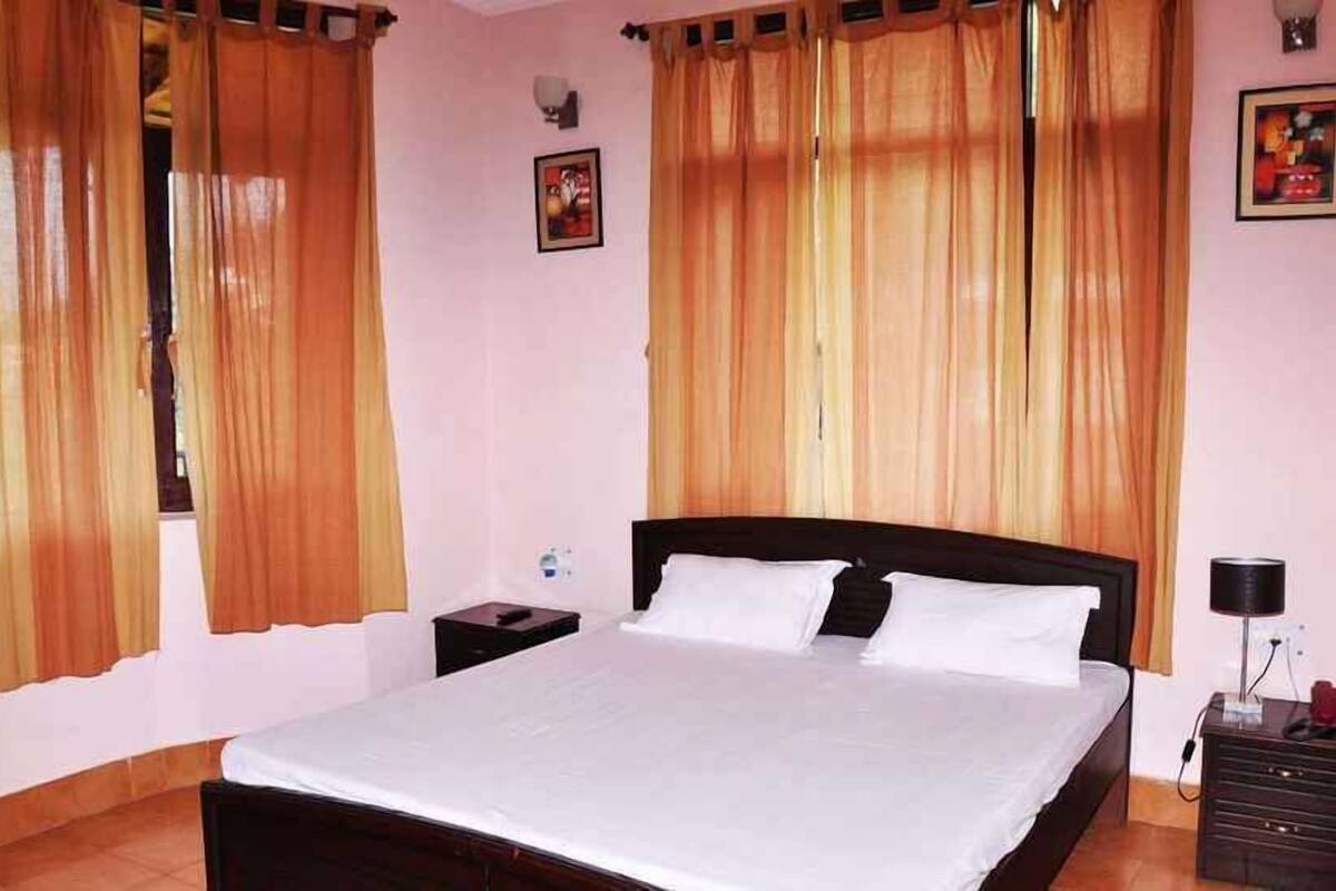A bedroom with a bed, two nightstands, a lamp, and curtains.