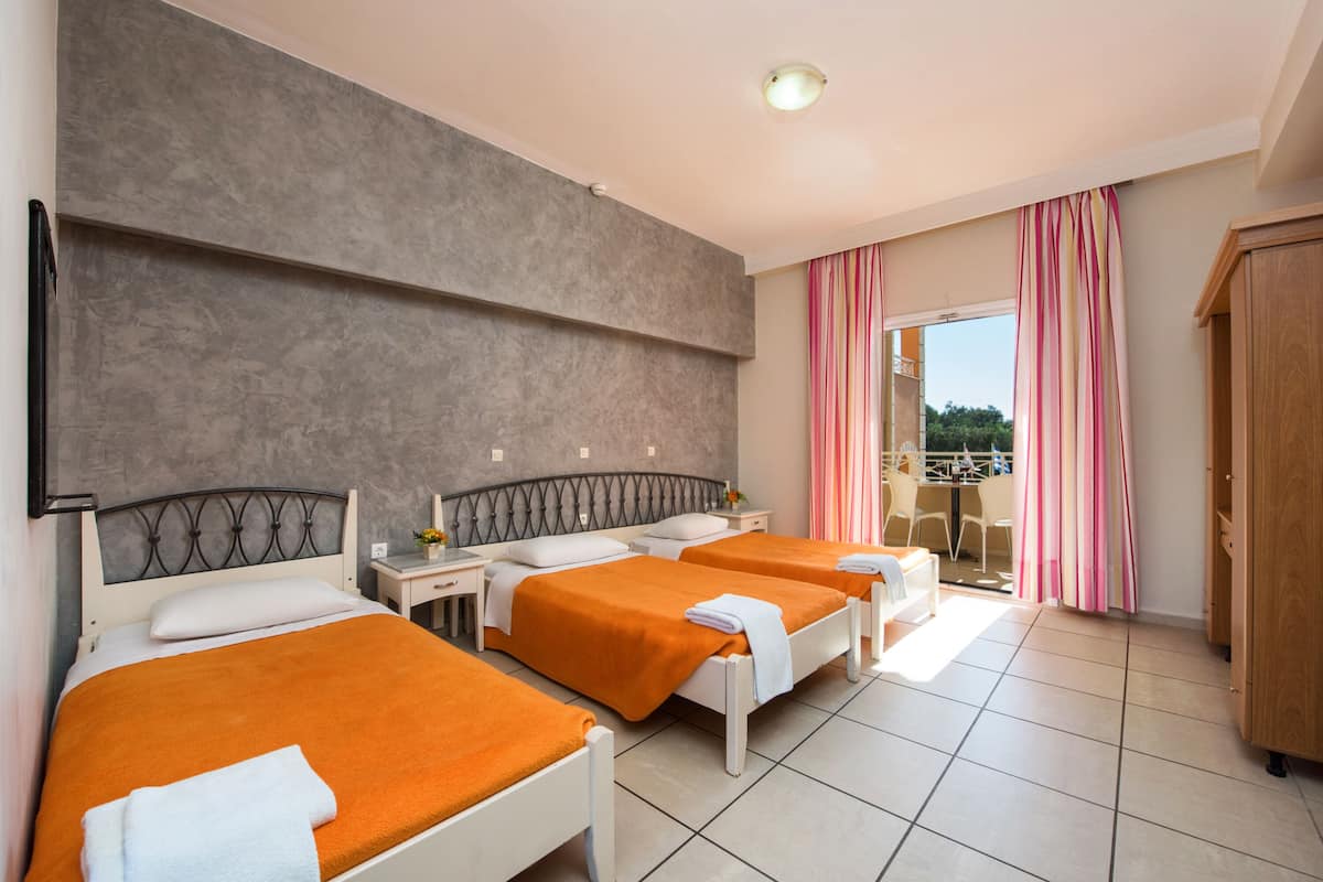 A hotel room with two beds, a large window with curtains, a wooden wardrobe, and a balcony with a view.
