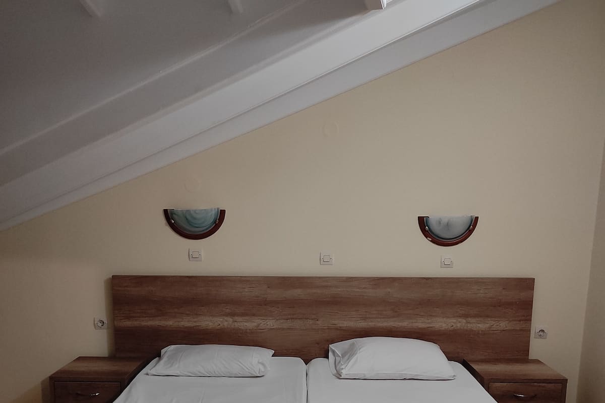 A double bed with two nightstands, a wooden headboard, and a skylight above.