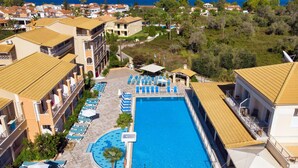 Un resort con una amplia piscina, tumbonas y vistas al mar.