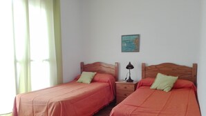 Two single beds with wooden headboards, a nightstand with a lamp, and a painting on the wall. - LARGE TERRACE 60 M2, SEA VIEWS. Wi-Fi exclusive (Isleta del Moro)