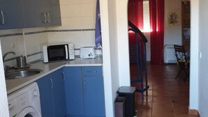 A compact kitchen with a washing machine, microwave, and blue cabinets. - LARGE TERRACE 60 M2, SEA VIEWS. Wi-Fi exclusive (Isleta del Moro)