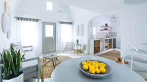A modern, white-themed living room with a round table, a bowl of lemons, and a potted plant. - 360 Caldera View Villa by Caldera Houses (Santorini)