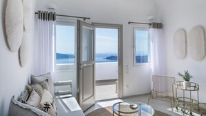 A modern room with a view of the sea, a sofa, a chair, and a small table. - 360 Caldera View Villa by Caldera Houses (Santorini)
