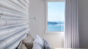 A bedroom with a view of the sea, a window with curtains, and a bed with pillows. - 360 Caldera View Villa by Caldera Houses (Santorini)