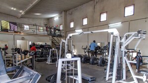 Een sportschool met diverse fitnessapparaten, waaronder loopbanden, krachtapparaten en losse gewichten.