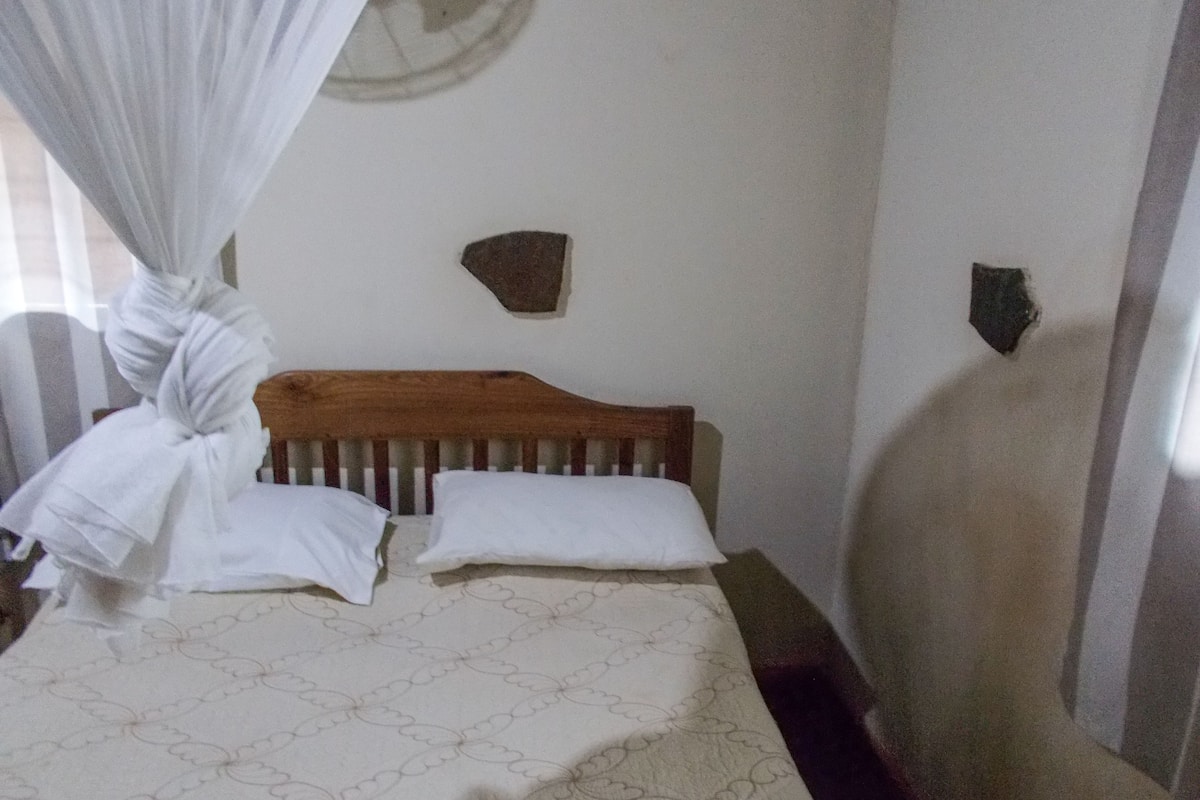 A bedroom with a wooden headboard, two white pillows, and a patterned bedspread.