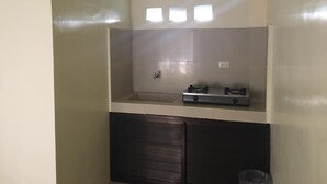 Uma cozinha compacta com fogão embutido, uma pia pequena e uma janela sobre o balcão.