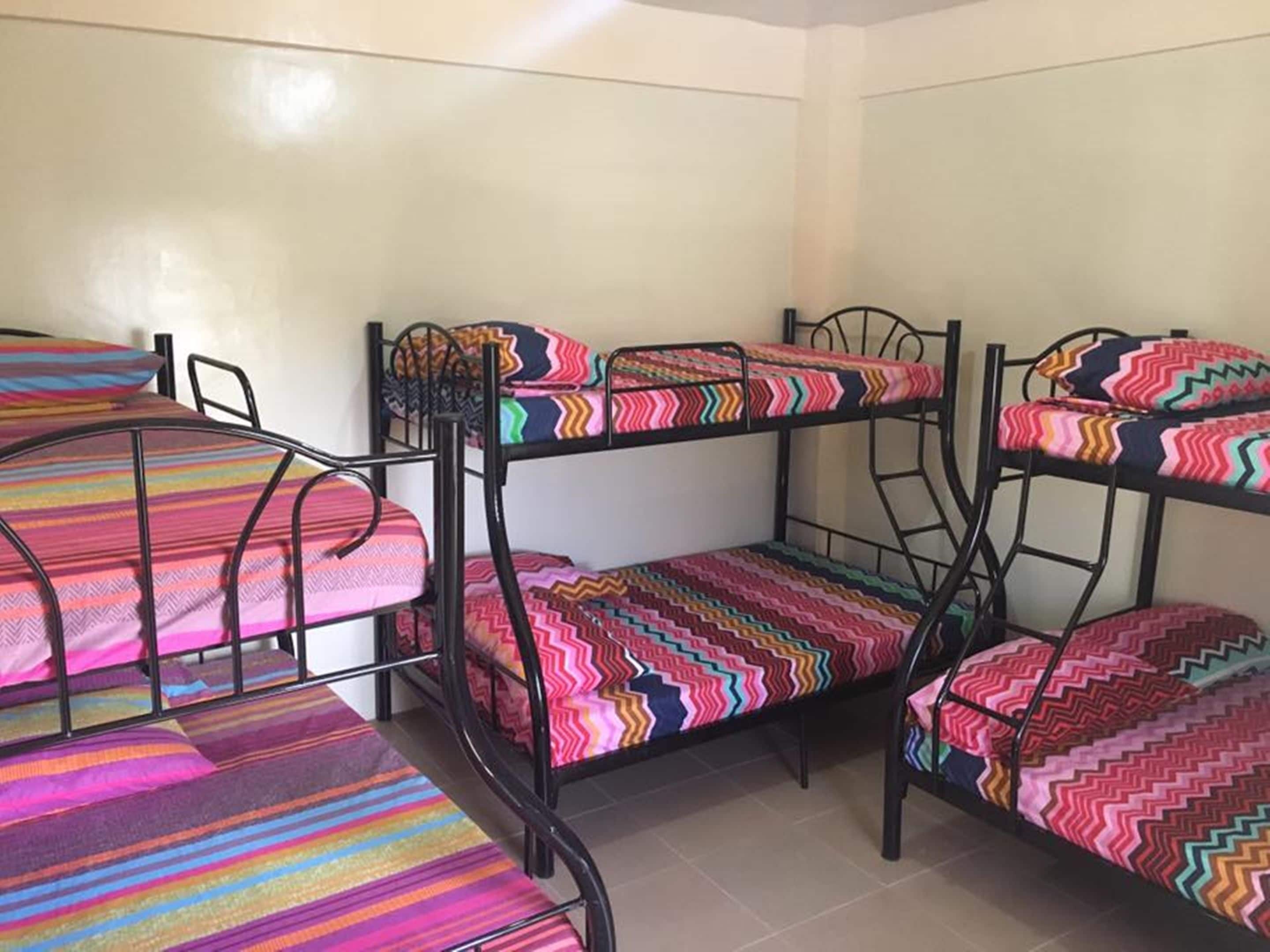 A dormitory with bunk beds, each with colorful striped bedding.