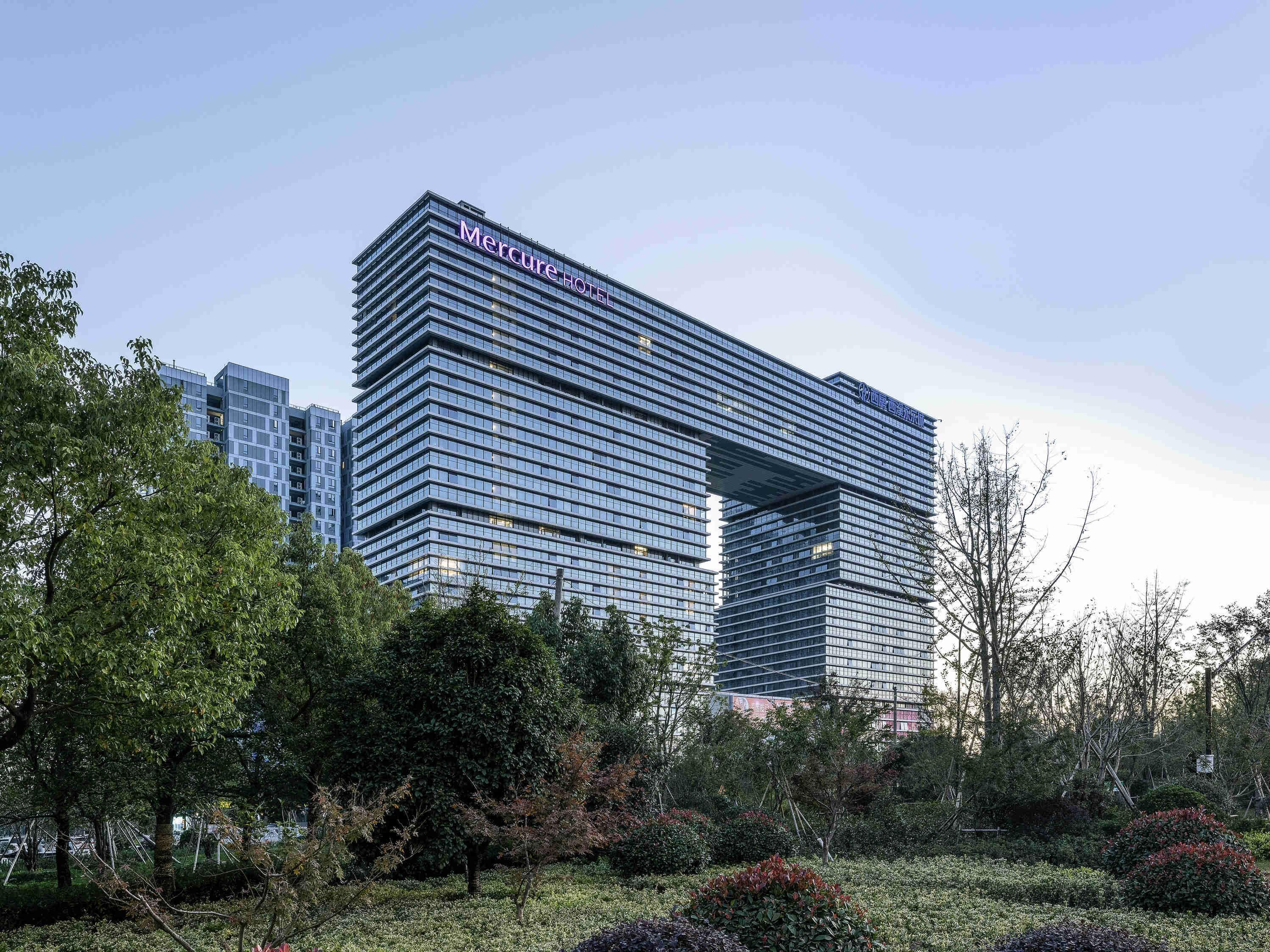 Un hotel moderno con un diseño arquitectónico distintivo, que presenta un amplio frente de vidrio y una entrada destacada.