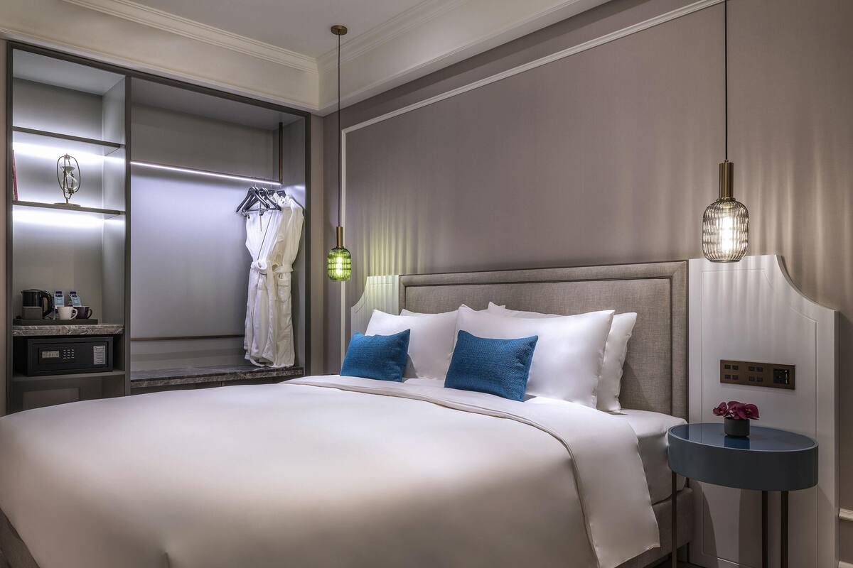 Una habitación de hotel con una cama grande, una mesita de noche y una pequeña mesa redonda con una lámpara.