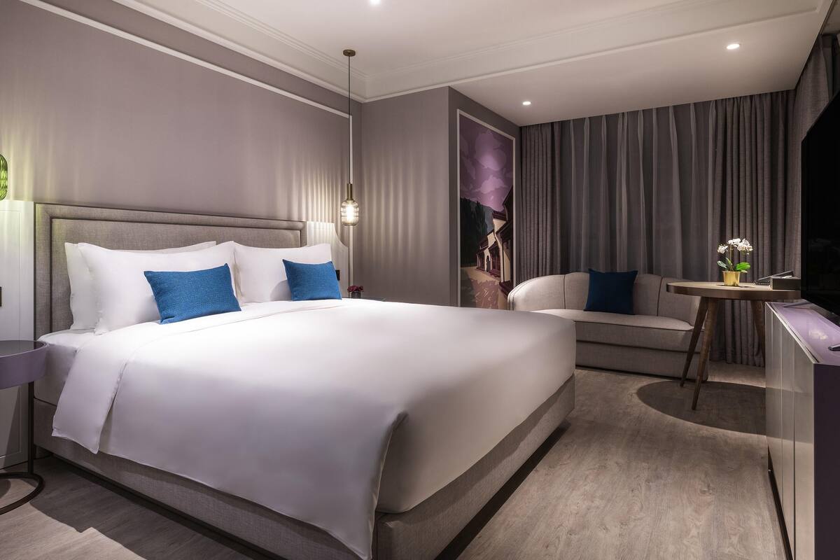 Una habitación de hotel moderna con una cama grande, un escritorio y un sofá.
