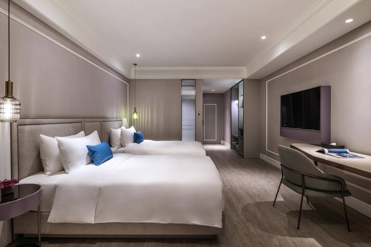 Habitación de hotel con una cama grande, un escritorio, una silla, un televisor y un vestidor.