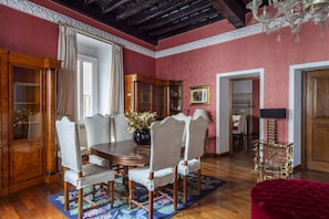 A dining room with a wooden table, upholstered chairs, a vase with flowers, and a chandelier.