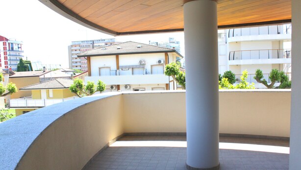 Un balcon doté d’un sol carrelé, d’un plafond en bois et d’un pilier blanc.