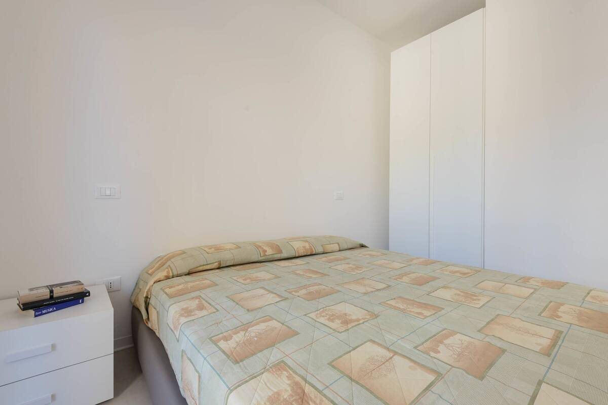 Um quarto com cama, mesa de cabeceira e guarda-roupa.