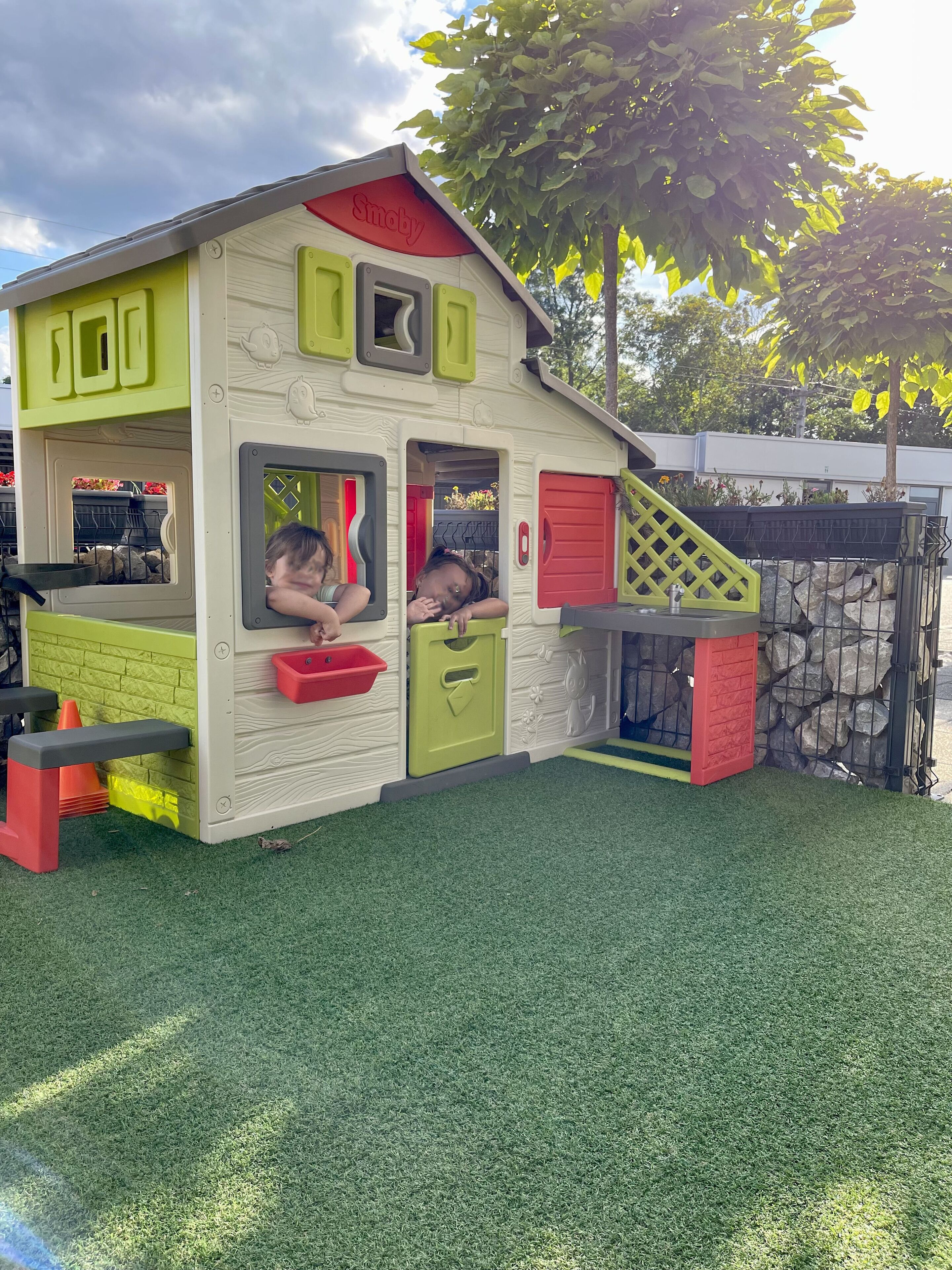 Ein Spielhaus für Kinder mit einer Rampe, Fenstern und einer Tür.