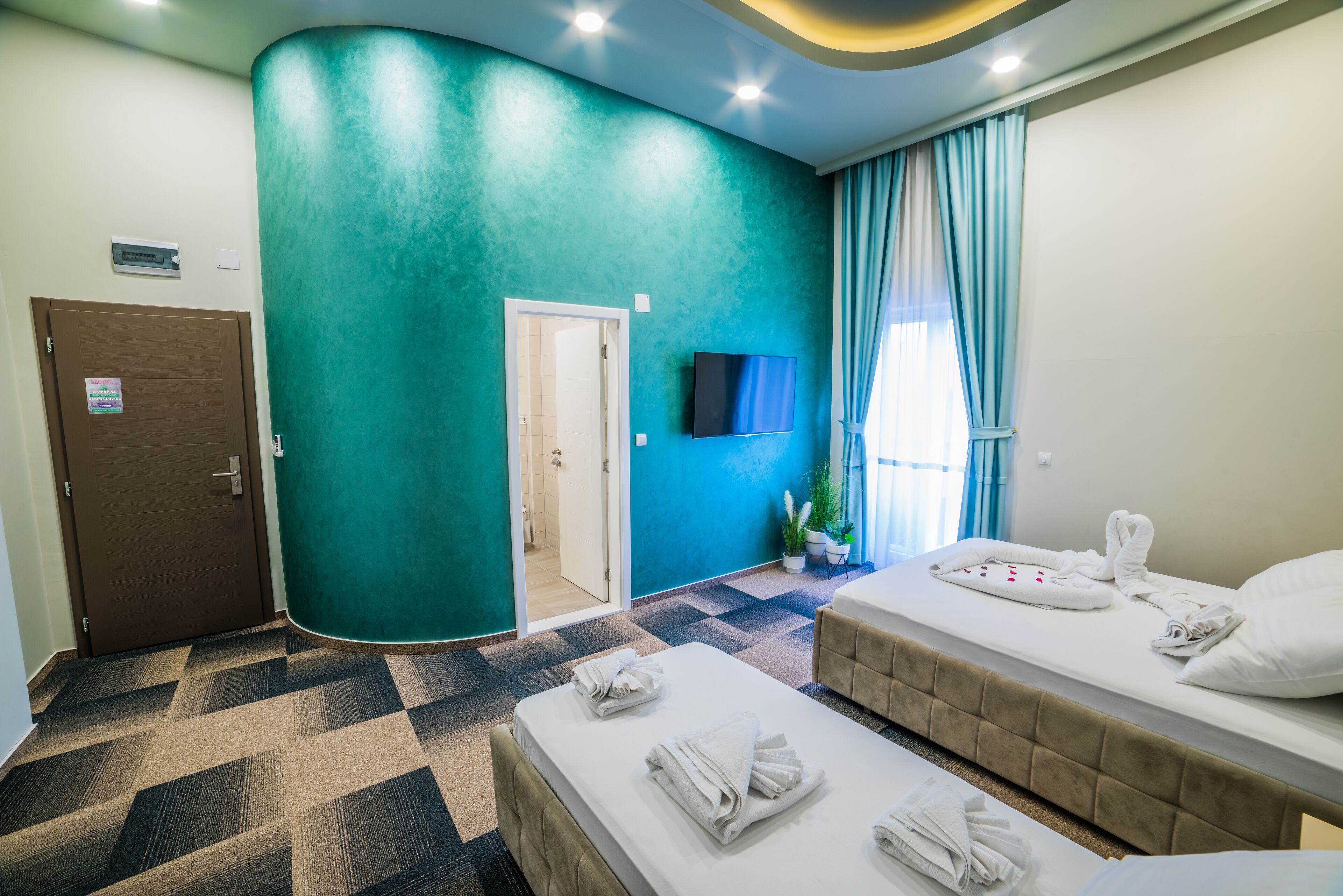 Une chambre d’hôtel avec deux lits, une télévision, une porte et une salle de bain visible à travers une porte ouverte.