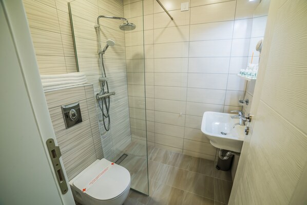 Un baño moderno con ducha de vidrio, inodoro blanco y lavamanos.