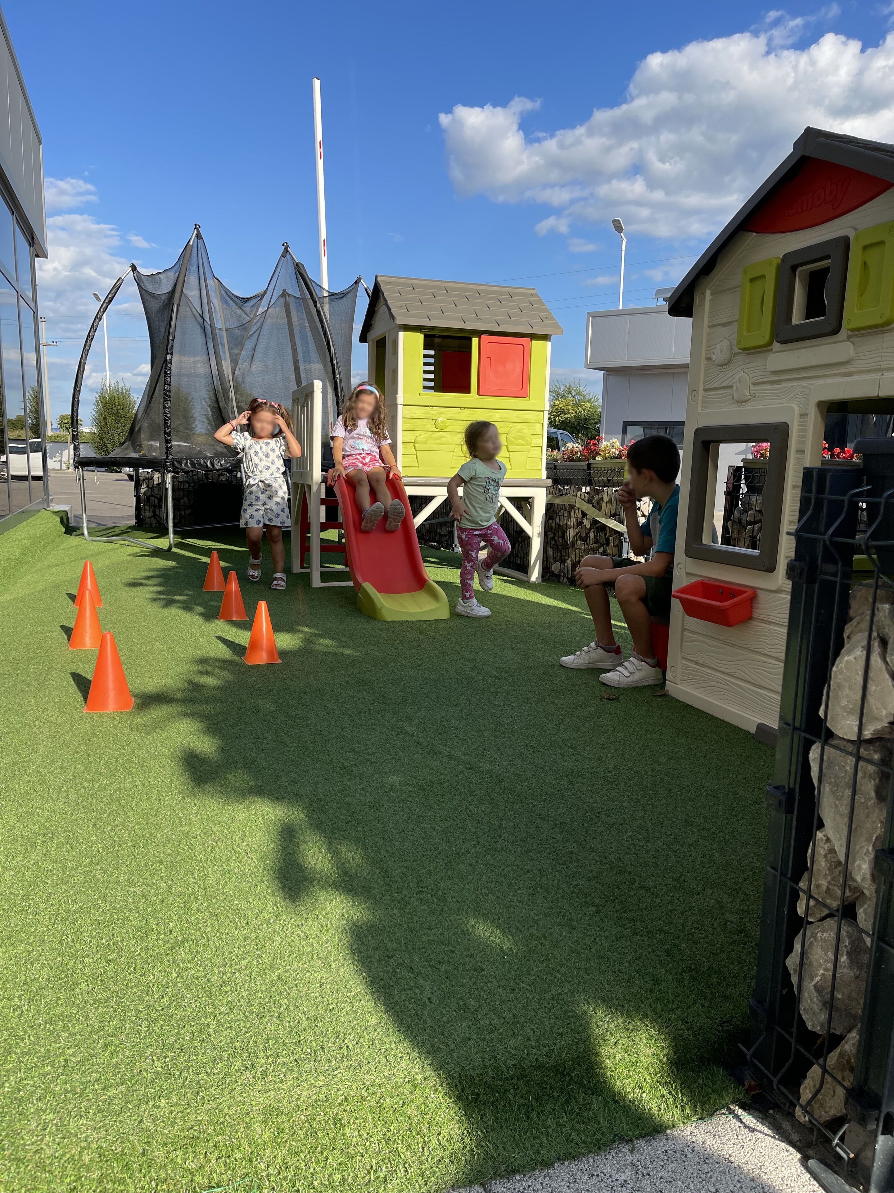 A playground with artificial grass, a slide, and play structures.