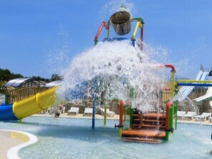 A water play area with a large bucket and water jets, surrounded by a pool and slides. - Camping Le Soleil de la Méditerrannée (Saint-Cyprien)