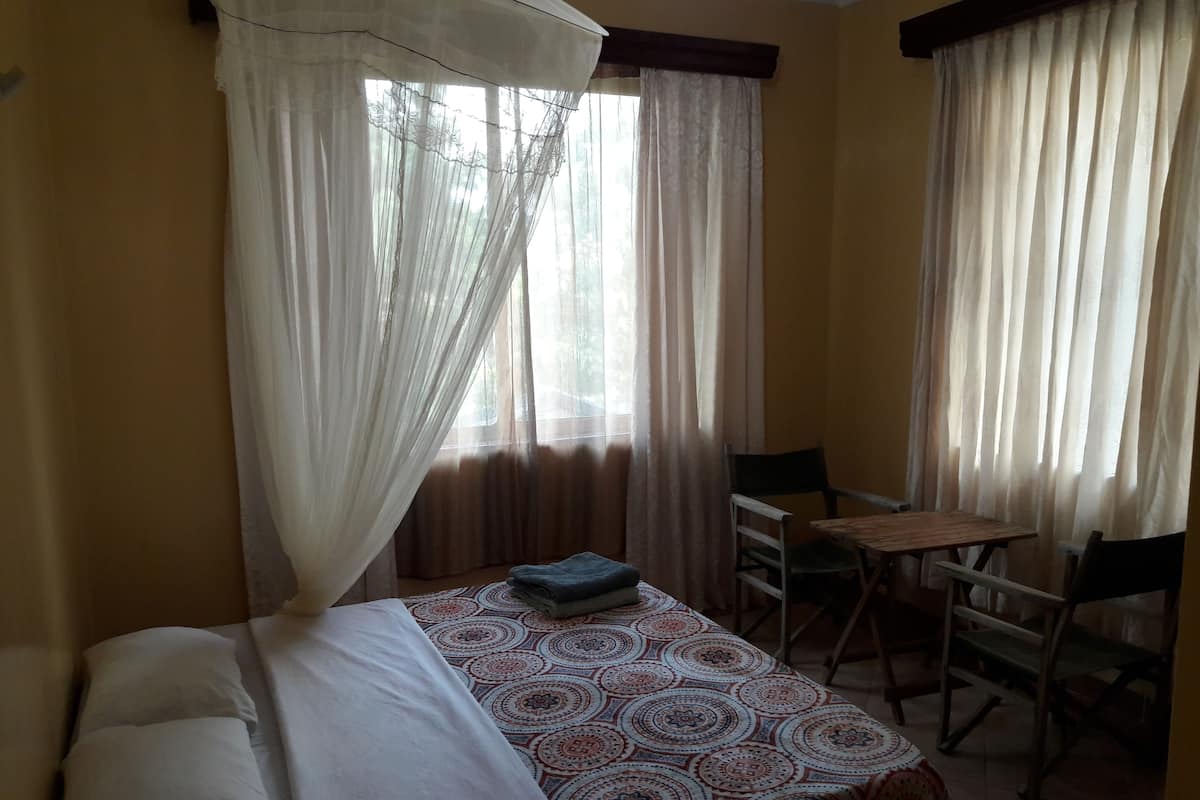 A room with a bed, a table, and two chairs.