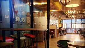 En restaurantindretning med høje borde og skamler, et mønstret gulv og store vinduer.