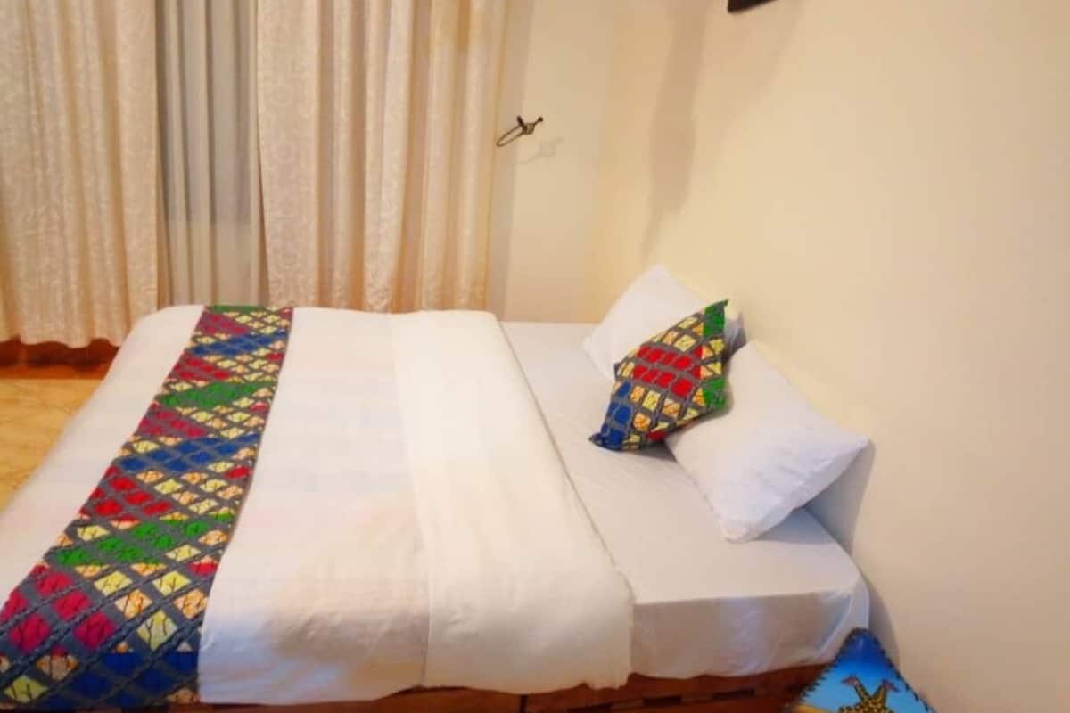 A bed with a colorful quilt, white pillows, and a wooden headboard.