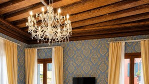 Ein Hotelzimmer mit einem großen Bett, einem Schreibtisch, einem Stuhl, einem Fernseher und einer Kristallleuchtre.