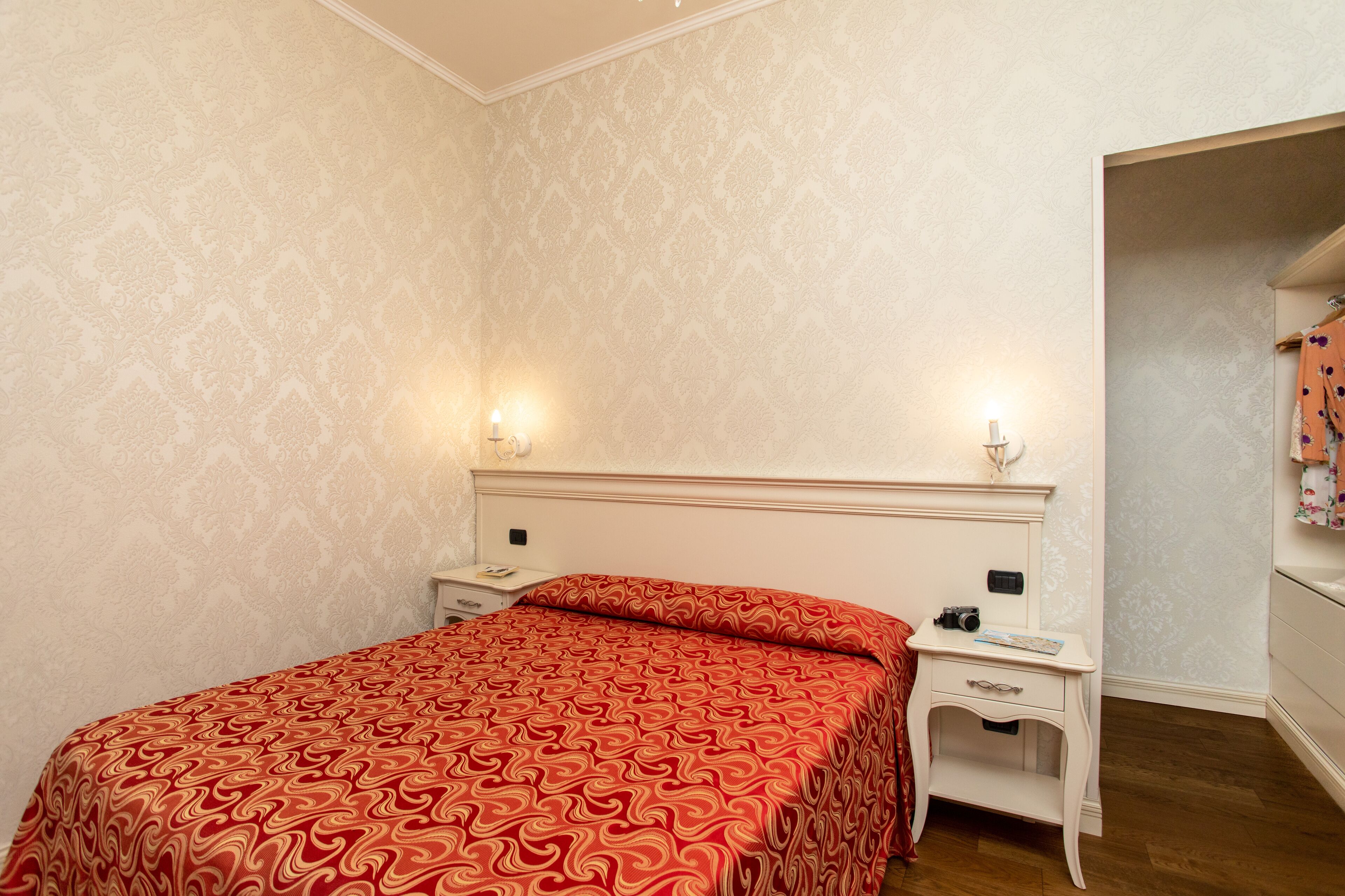 Une chambre à coucher avec une couvre-lit à motifs, des lampes de chevet, une table de chevet et une armoire.