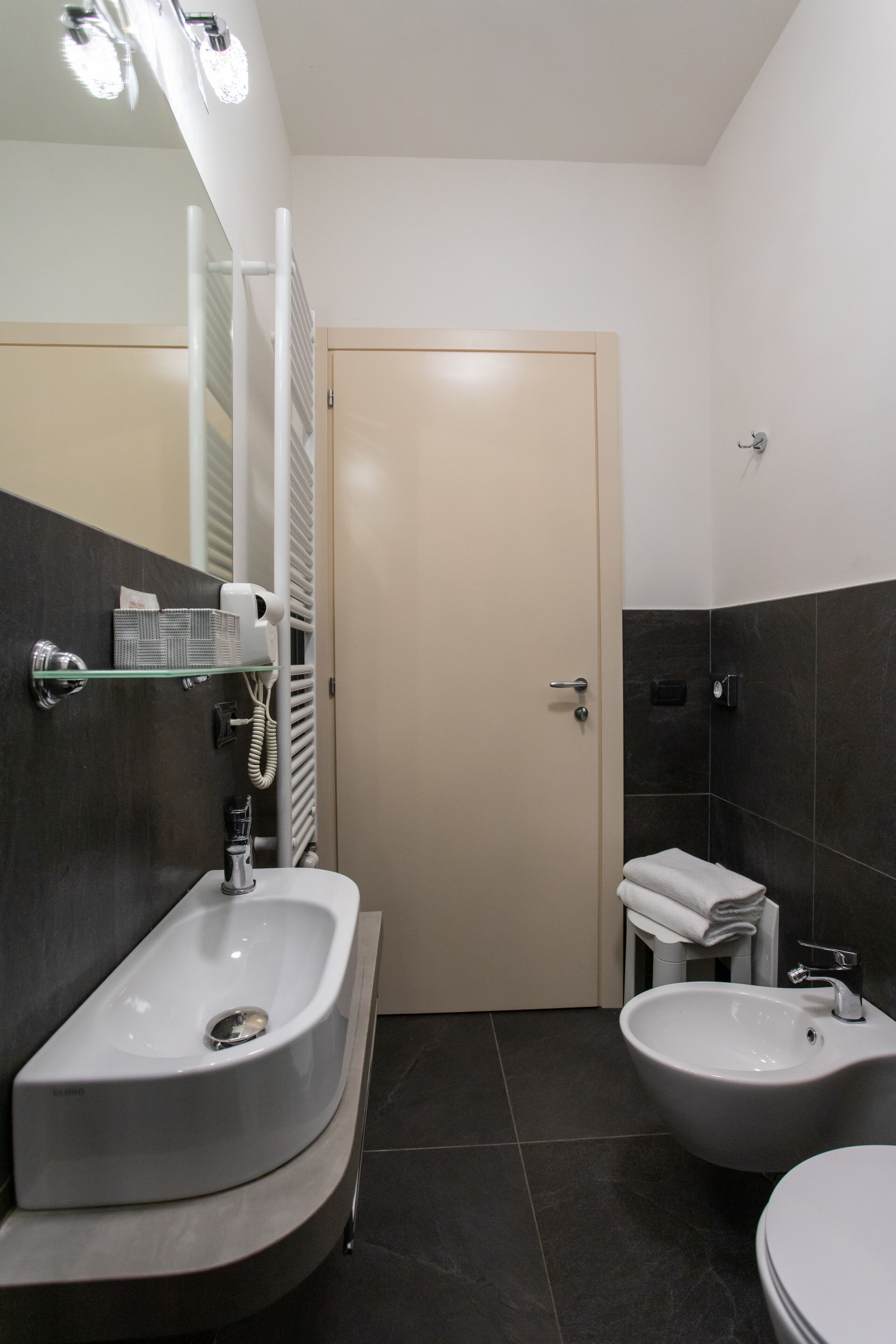 A modern bathroom with a curved sink, bidet, and a toilet.