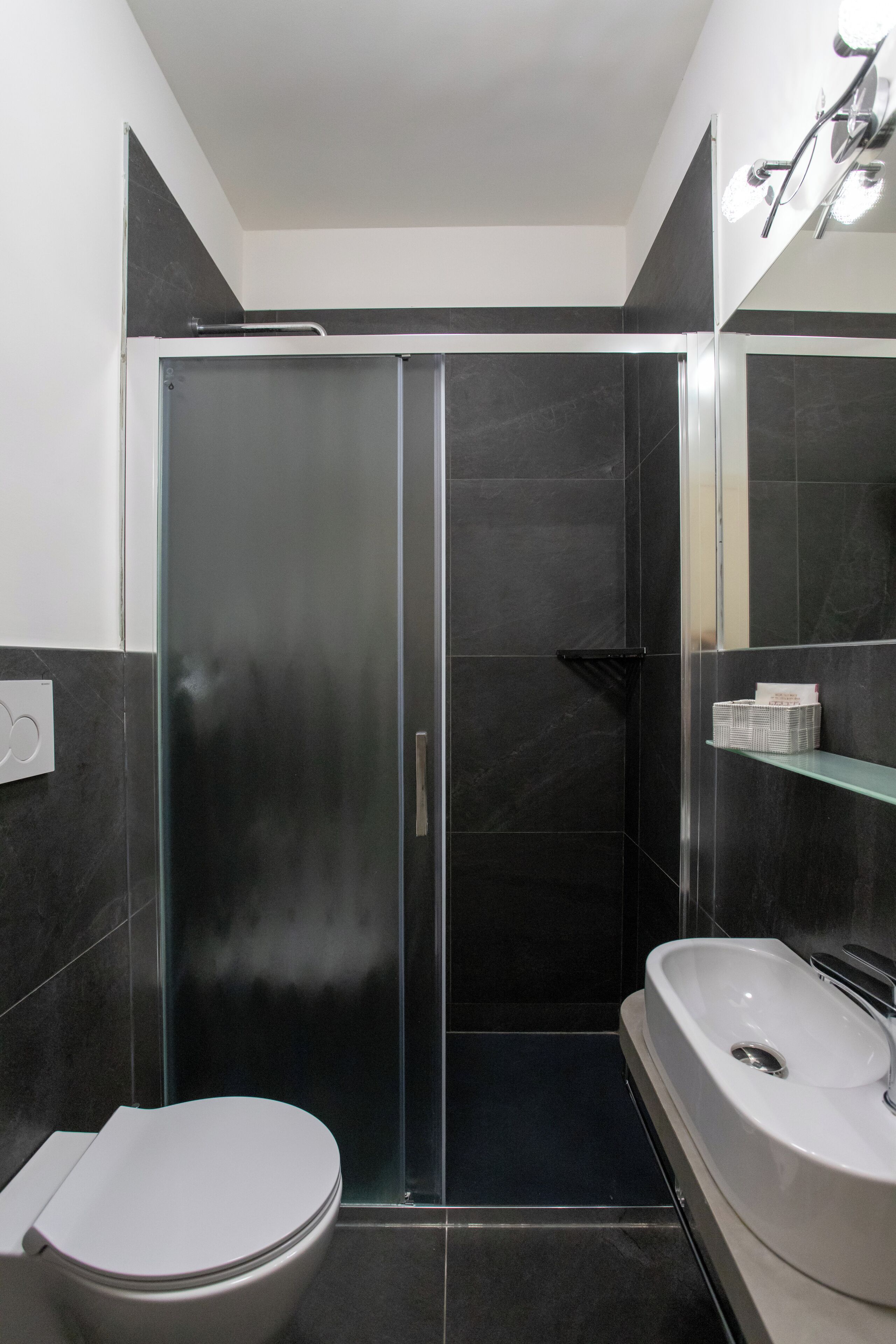 A modern bathroom with a glass-enclosed shower, a white toilet, and a vanity with a sink.
