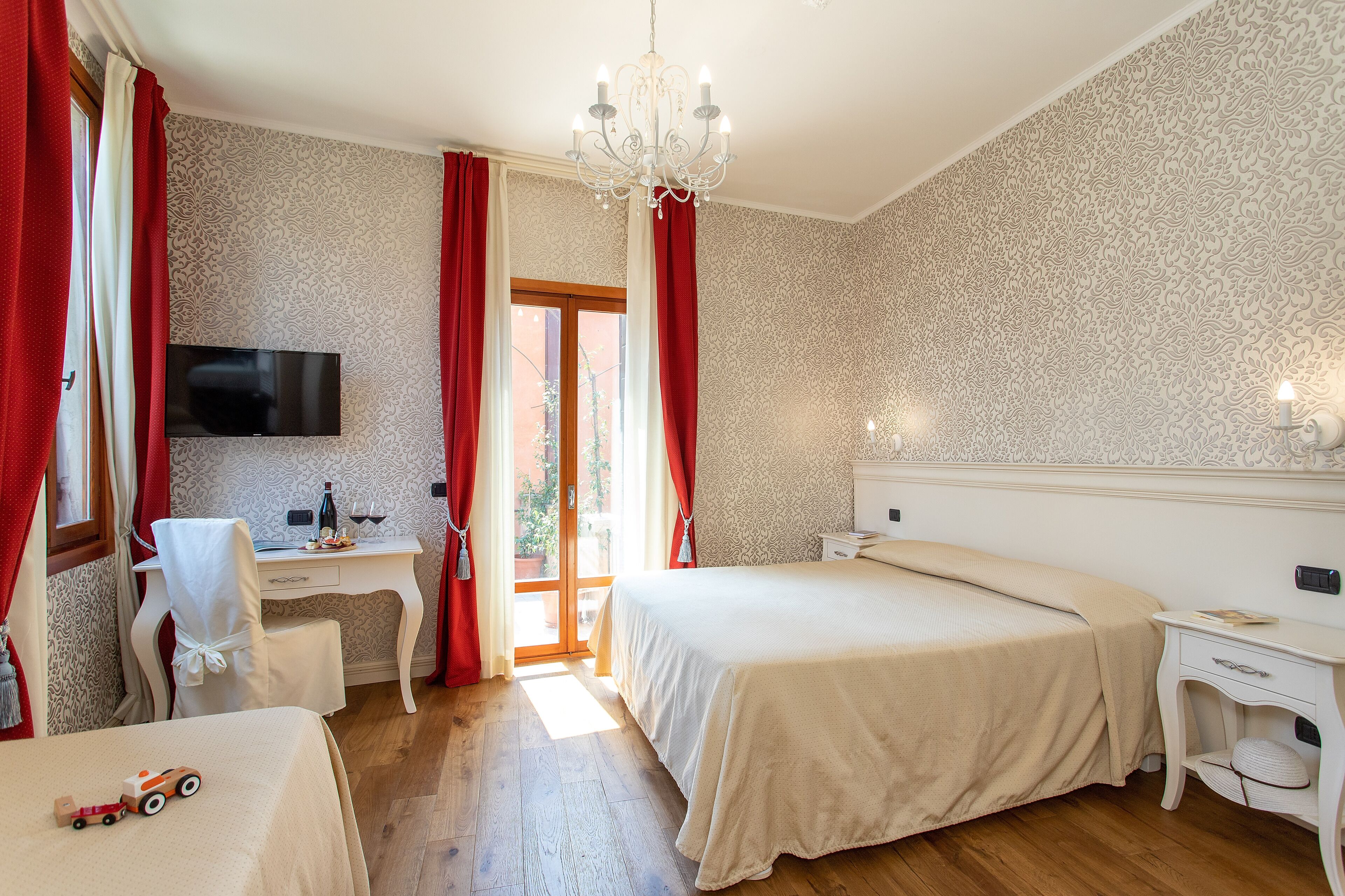 Ein Hotelzimmer mit Bett, Schreibtisch, Sessel, Fernseher und einer Kristallleuchtre.