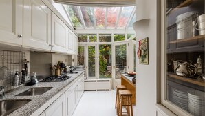 Een moderne keuken met witte kasten, granieten aanrechtbladen, een dakraam en uitzicht op bomen.