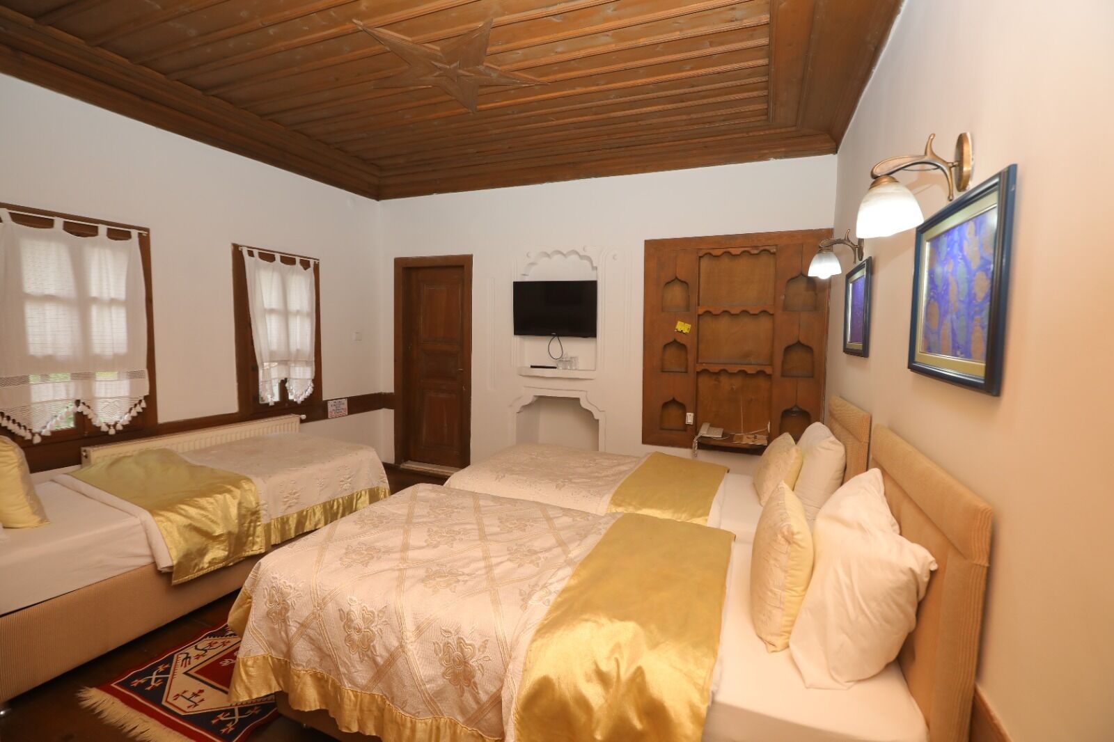 A room with two beds, a television, and a wooden ceiling.