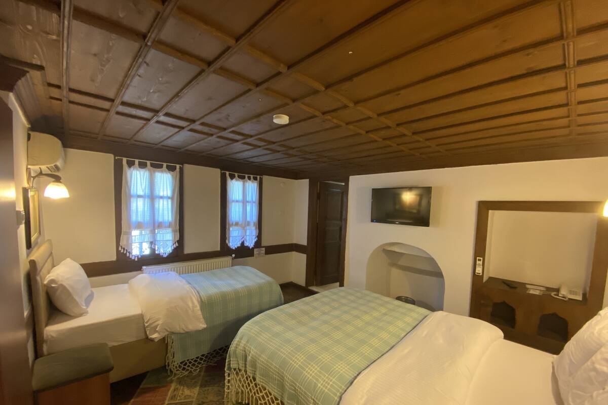 Une chambre avec deux lits, une télévision, un radiateur et une porte dotée d’un miroir.