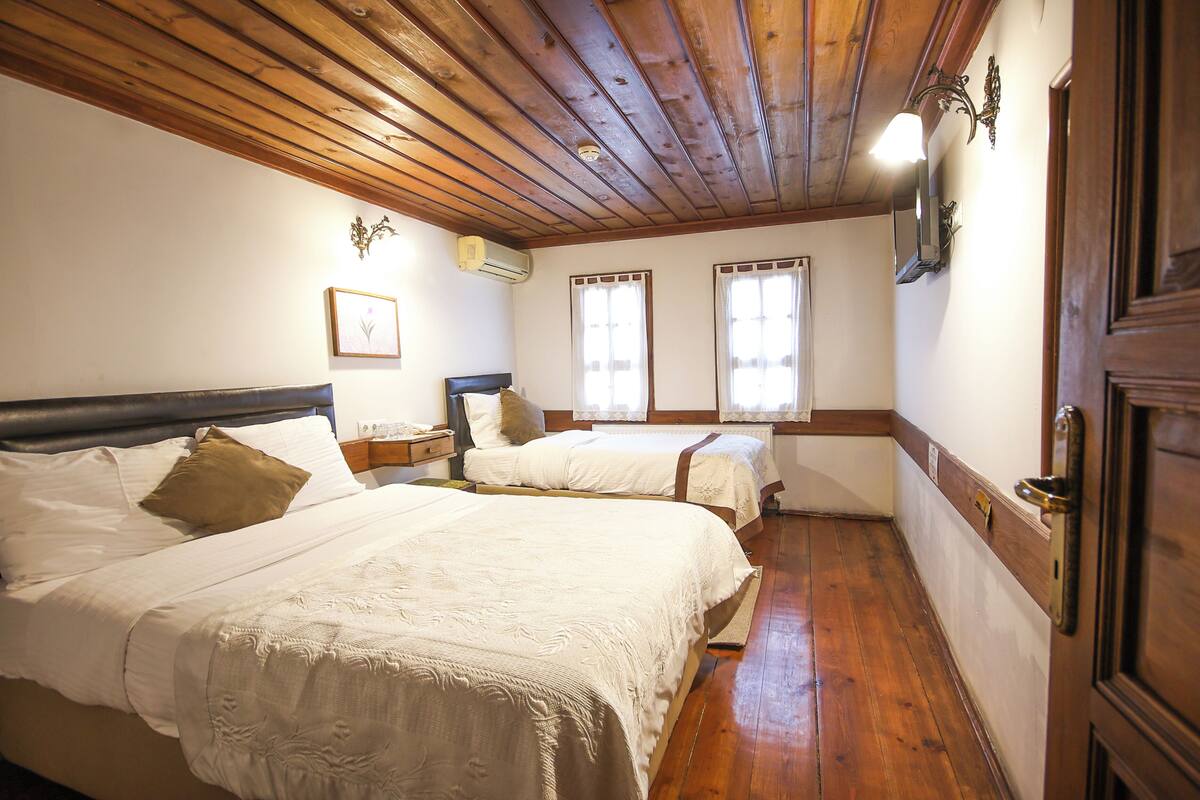 Une chambre avec deux lits, un plancher en bois, un plafond en bois et une porte.