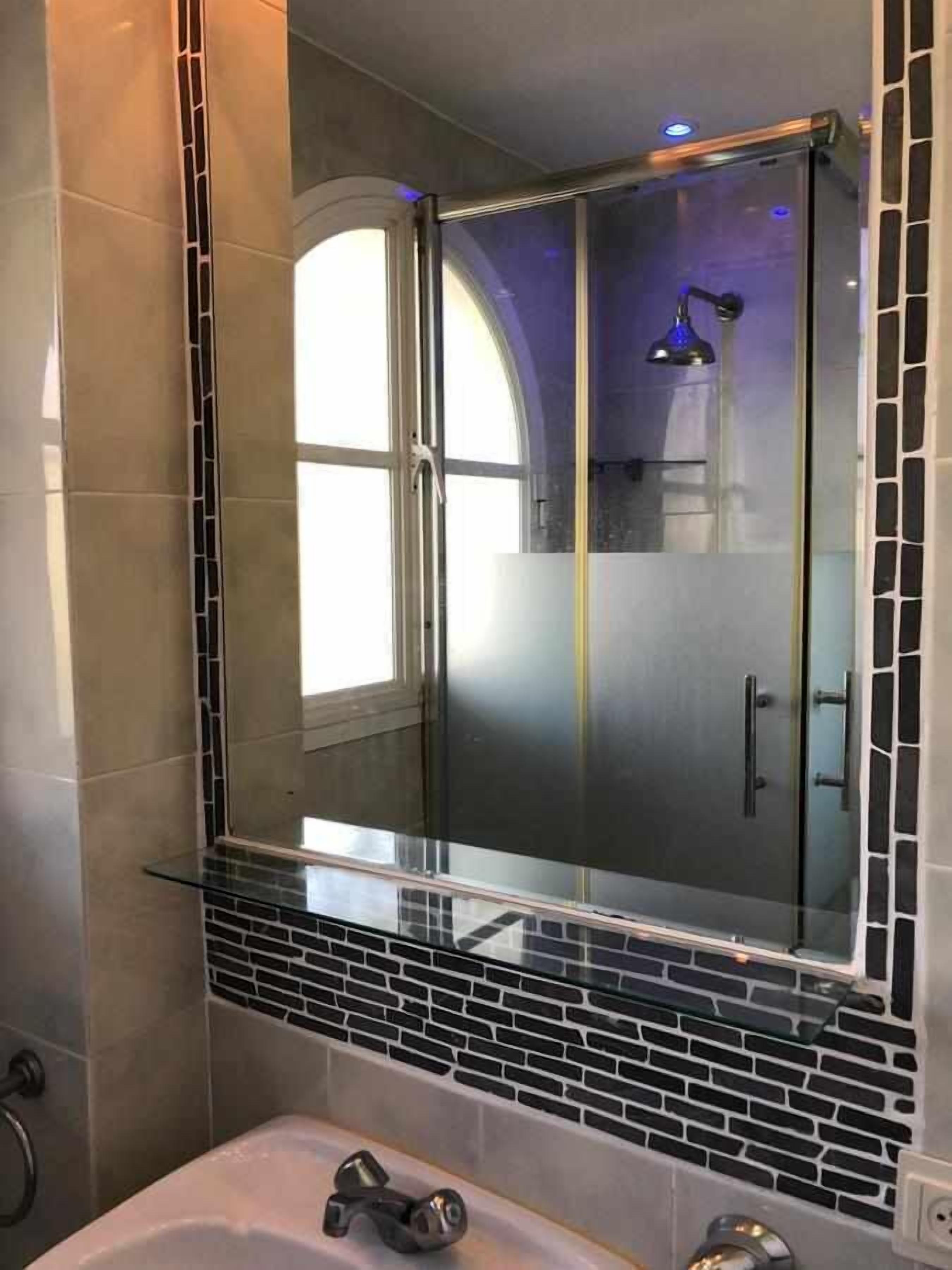 Un baño con cabina de ducha de vidrio, suelo de baldosas y bañera.