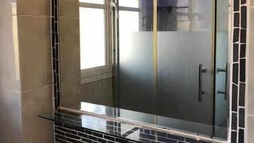 Un baño con cabina de ducha de vidrio, suelo de baldosas y bañera.