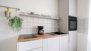 A kitchen with white cabinets, a wooden countertop, a coffee maker, a sink, and a microwave. - Apartments Lotea (Konavle)