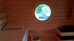 A wooden cabin with a circular window, wooden benches, and a wooden bucket. - Eifel Dream Landhaus (Plütscheid)