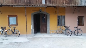 Ein Gebäude mit gelber Fassade, einer Holztür und mehreren Fahrrädern davor.