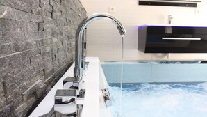 A modern bathroom with a stone wall, a chrome faucet, and a bathtub filled with water. - Eifel Dream Ardennenblick (Roth bei Prüm)