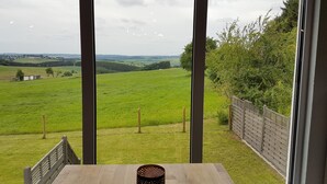 A room with a large window overlooking a green field and distant hills. - Eifel Dream Ardennenblick (Roth bei Prüm)