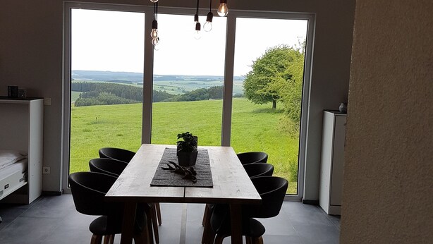 A dining area with a large table, chairs, and hanging light fixtures. - Eifel Dream Ardennenblick (Roth bei Prüm)